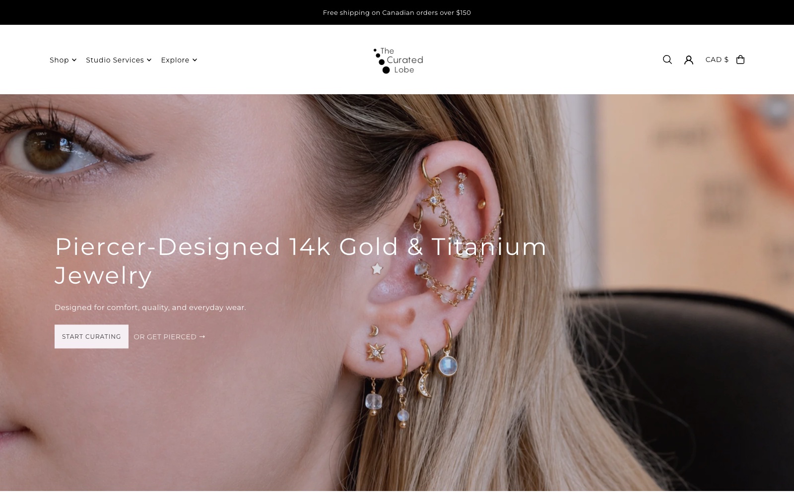The Curated Lobe homepage: “Piercer-Designed 14k Gold & Titanium Jewelry” over a close photo of an ear wearing gold earrings